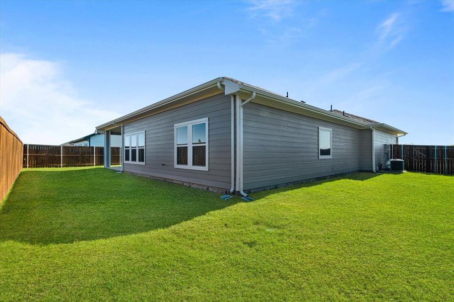 View of home's exterior featuring cooling unit and a lawn