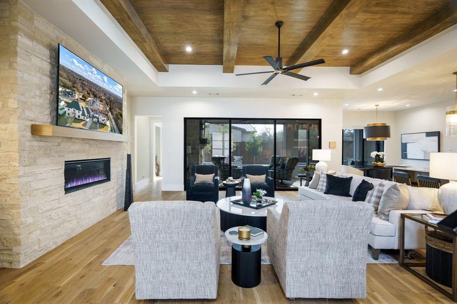 Living room with ceiling fan, beam ceiling, a fireplace, wooden ceiling, and light wood-type flooring