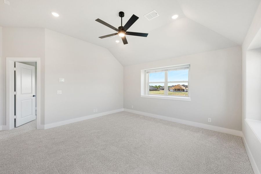 Empty bedroom with vaulted ceiling, black ceiling fan, carpet flooring, and a single window Empty bedroom with vaulted ceiling, black ceiling fan, carpet flooring, and a single window