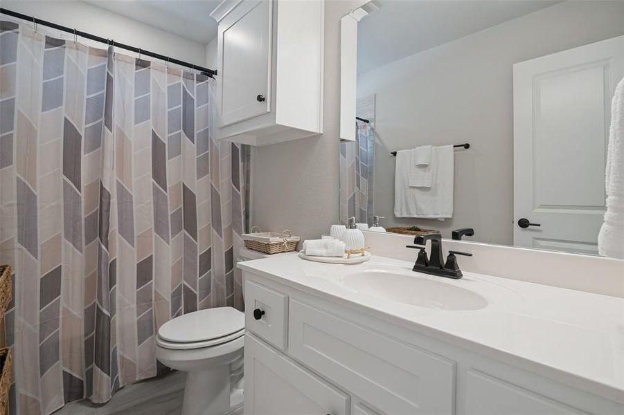 Bathroom featuring a white vanity with integrated sink, black two-handle faucet, and an overhead mirror