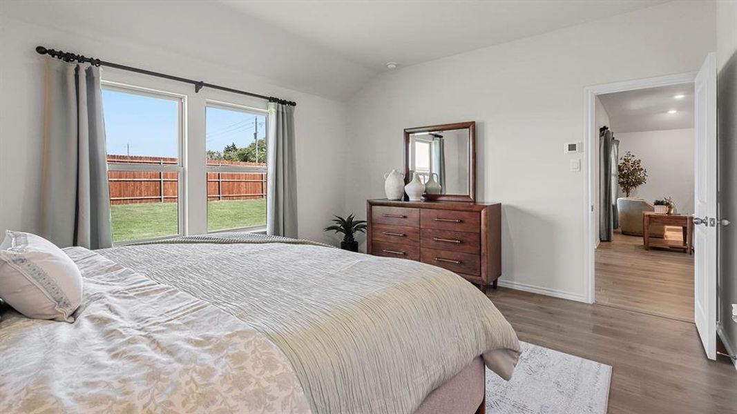 Bright room featuring two windows overlooking a fenced yard with a lawn, and wood-look flooring