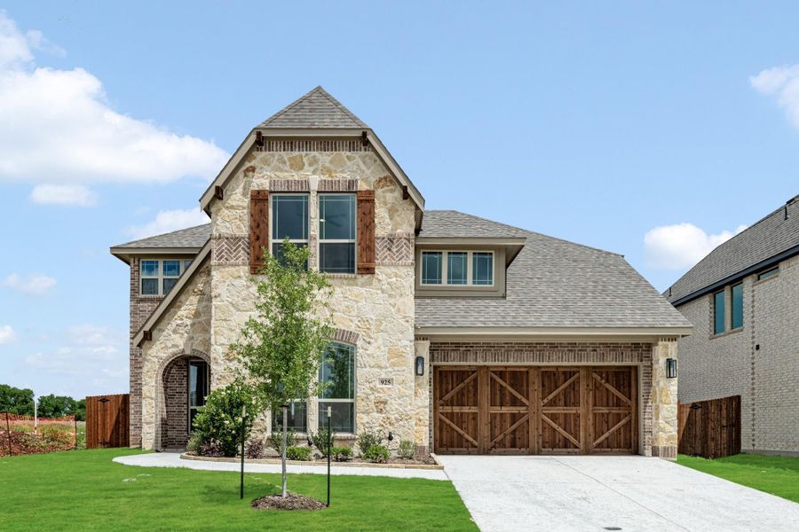 Two-story home with stone and brick exterior, wood garage doors, arched entry, and green front lawn Two-story home with stone and brick exterior, wood garage doors, arched entry, and green front lawn