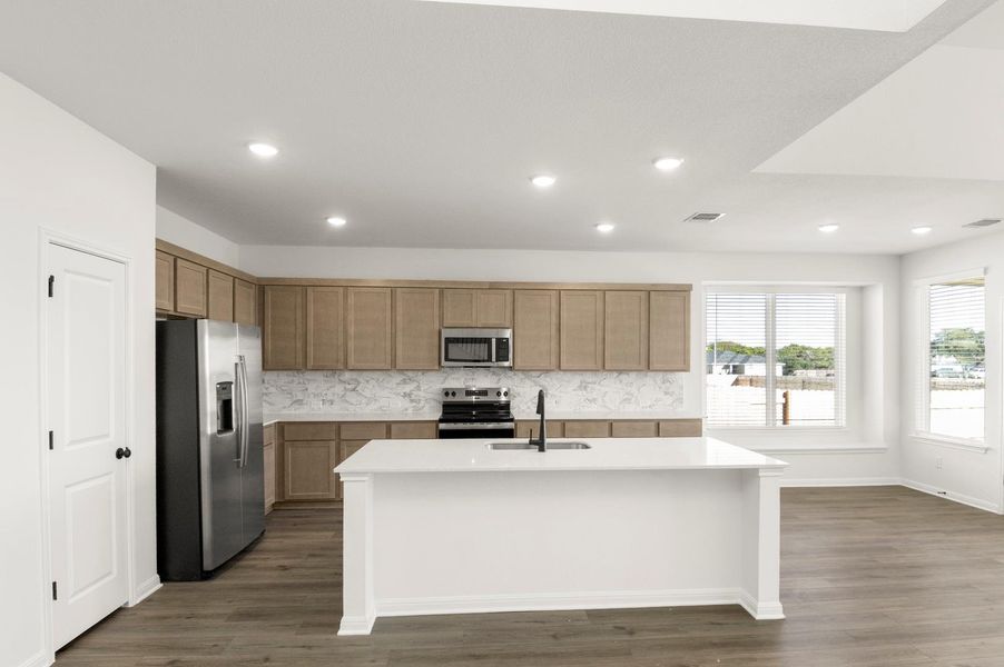Kitchen featuring stainless steel appliances, an island with sink, decorative backsplash, dark wood-style floors, and recessed lighting