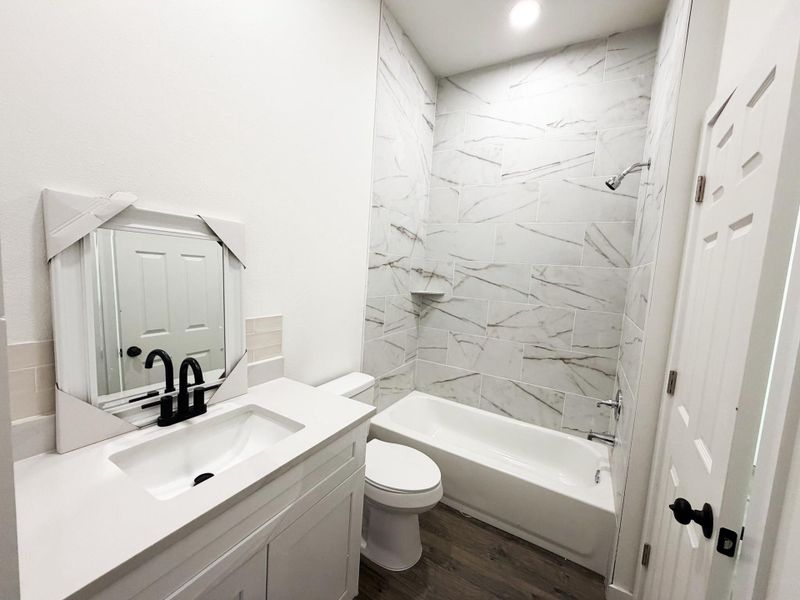 Bathroom featuring a white vanity with an integrated sink, matte black faucet, and a large mirror Bathroom featuring a white vanity with an integrated sink, matte black faucet, and a large mirror