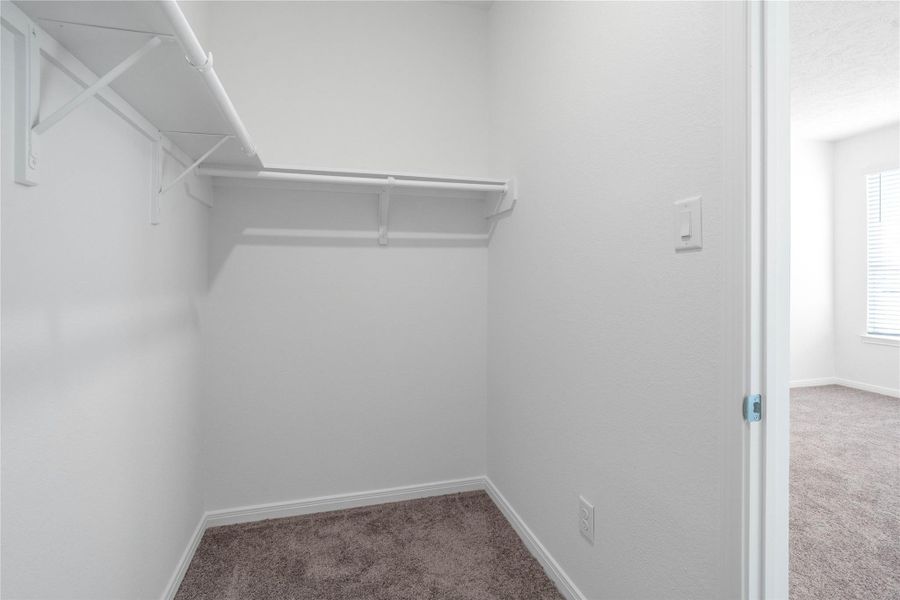 The spacious primary bedroom walk-in closet offers shelving, hanging rods, and ample storage space to keep your wardrobe organized.
