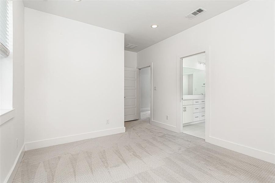 Unfurnished bedroom with light colored carpet, connected bathroom, and recessed lighting