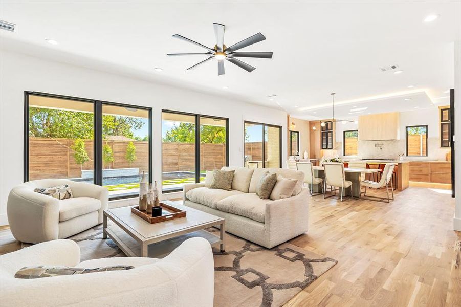 Living room with recessed lighting, light wood finished floors, and a ceiling fan Living room with recessed lighting, light wood finished floors, and a ceiling fan