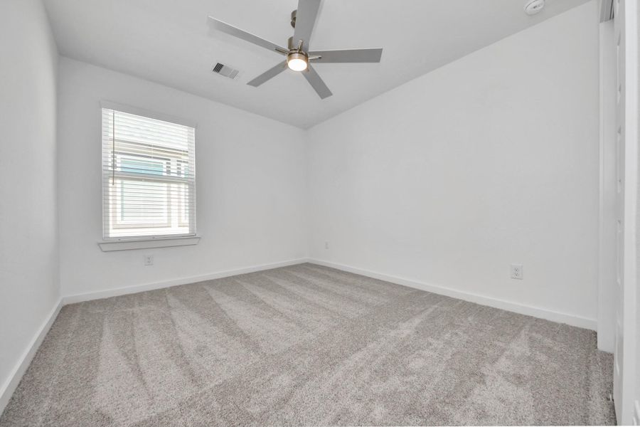 Secondary bedroom features plush carpeting, large windows that let in plenty of natural light, bright paint, and spacious closets. Sample photo of completed home with similar floor plan. Actual colors and selections may vary.