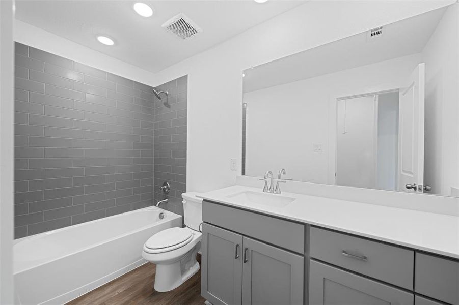 Full bathroom featuring toilet, hardwood / wood-style floors, vanity, and tiled shower / bath