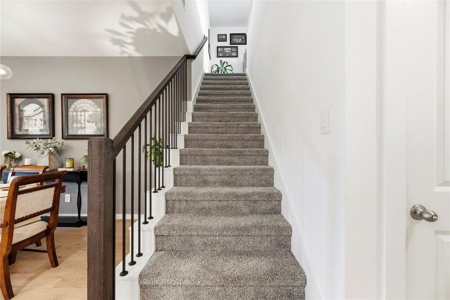 Carpeted staircase with wood handrail and iron balusters leading to the second-floor game room and bedrooms.
