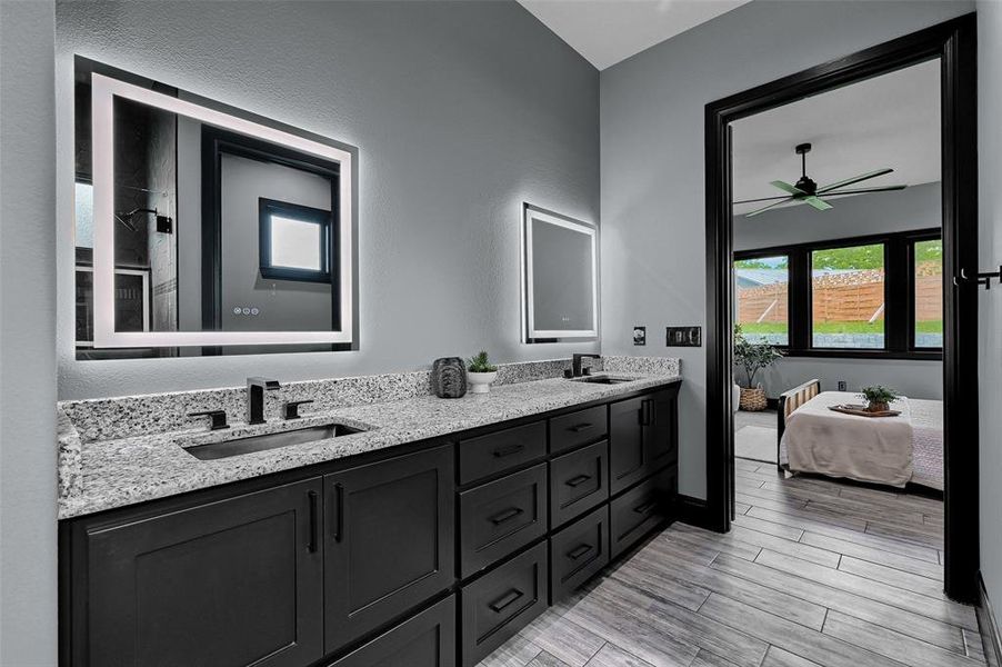 Full bath with double vanity, a ceiling fan, ensuite bath, wood finished floors, and baseboards Full bath with double vanity, a ceiling fan, ensuite bath, wood finished floors, and baseboards