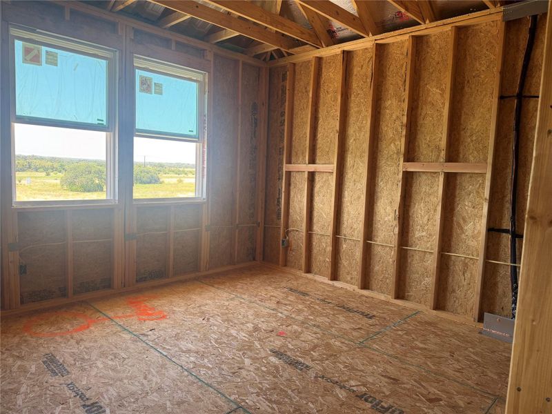 Framed windows overlook pasture views from an unfinished room under construction.