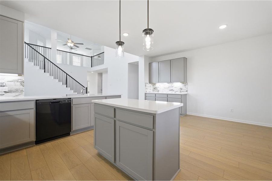 Kitchen with tasteful backsplash, gray cabinets, black dishwasher, and light wood finished floors
