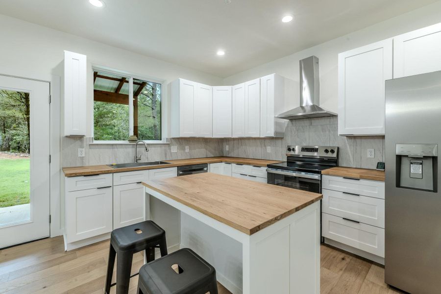 A well-appointed kitchen features a central island, modern stainless steel appliances, and sleek white cabinetry. A well-appointed kitchen features a central island, modern stainless steel appliances, and sleek white cabinetry.