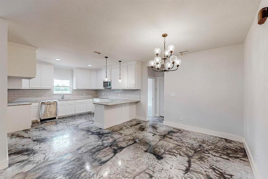 Kitchen featuring appliances with stainless steel finishes, backsplash, decorative light fixtures, an inviting chandelier, and white cabinets