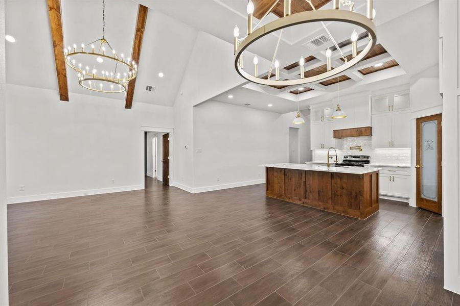 Kitchen featuring beam ceiling, high vaulted ceiling, glass insert cabinets, open floor plan, and an island with sink Kitchen featuring beam ceiling, high vaulted ceiling, glass insert cabinets, open floor plan, and an island with sink