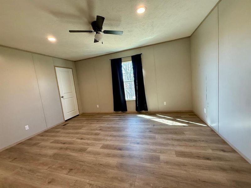 Empty room with a decorative wall, light wood finished floors, a ceiling fan, and recessed lighting Empty room with a decorative wall, light wood finished floors, a ceiling fan, and recessed lighting