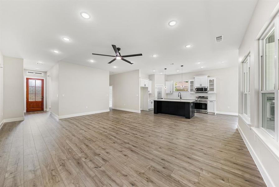 Unfurnished living room featuring recessed lighting, light wood finished floors, and ceiling fan Unfurnished living room featuring recessed lighting, light wood finished floors, and ceiling fan