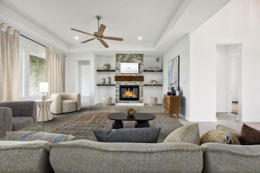 Living room with recessed lighting, ceiling fan, a stone fireplace, and a tray ceiling Living room with recessed lighting, ceiling fan, a stone fireplace, and a tray ceiling