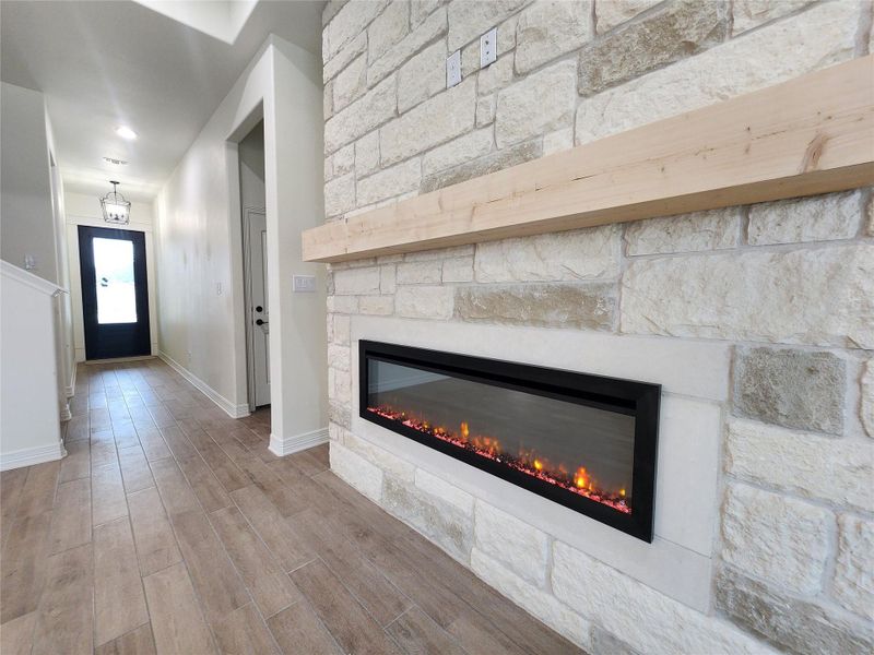 Stone accent wall featuring a linear electric fireplace with a wood-finish mantel
