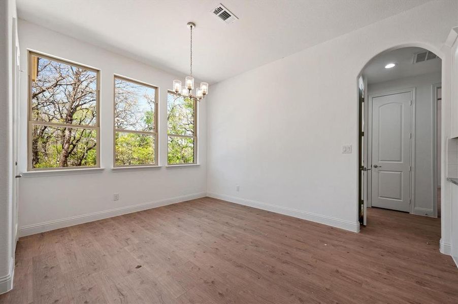 Unfurnished room featuring hardwood / wood-style floors and a chandelier