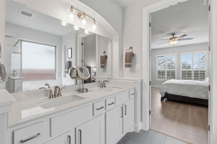 Bathroom with double vanity, ensuite bath, ceiling fan, light tile patterned flooring, and a marble finish shower