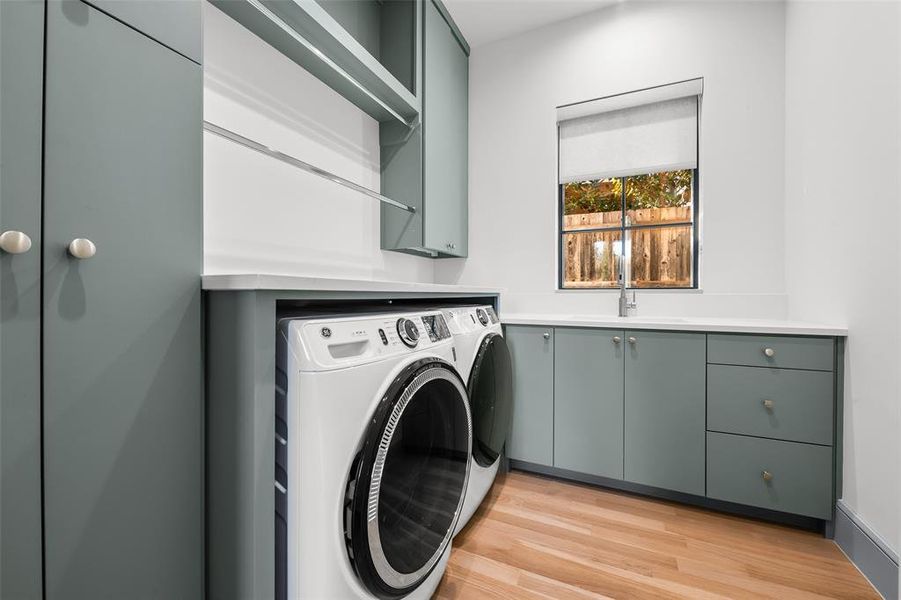 Laundry room with white oak hardwood floors, sink, custom storage cabinetry