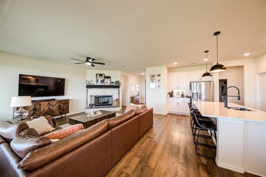 Living room with dark wood-style flooring, a fireplace, a ceiling fan, and recessed lighting