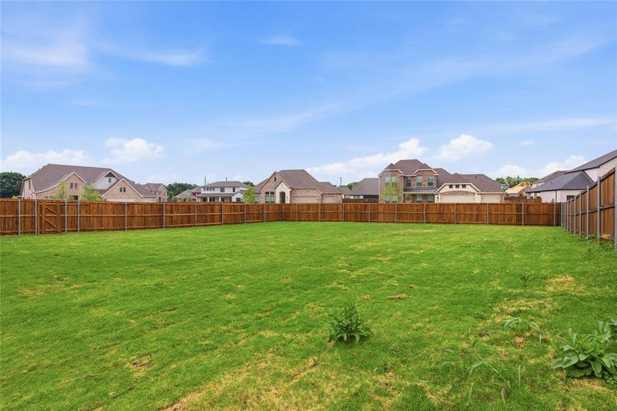 Expansive grassy yard area featuring a perimeter wood fence Expansive grassy yard area featuring a perimeter wood fence