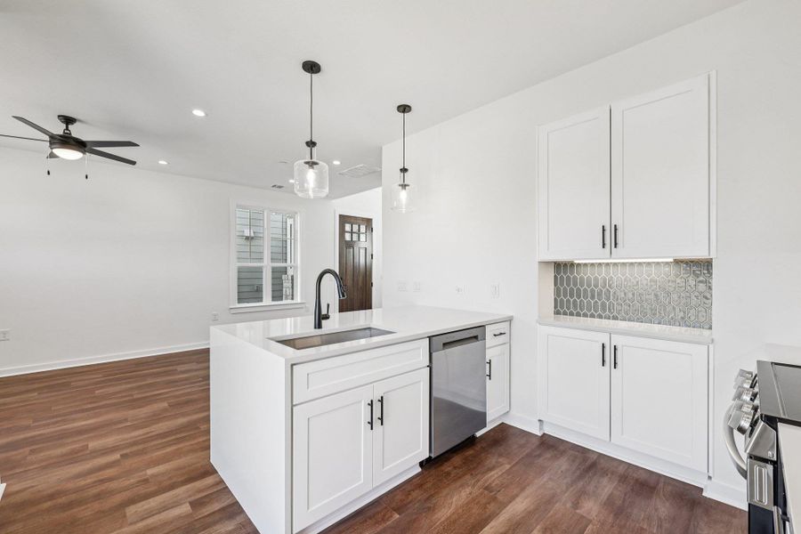 Kitchen featuring white cabinetry, recessed lighting, stainless steel appliances, a peninsula, and decorative light fixtures Kitchen featuring white cabinetry, recessed lighting, stainless steel appliances, a peninsula, and decorative light fixtures