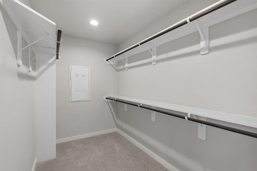 Spacious walk-in closet with shelving, high ceilings, custom paint, and sleek, dark modern finishes. Sample photo of completed home with similar floor plan. As-built interior colors and selections may vary.