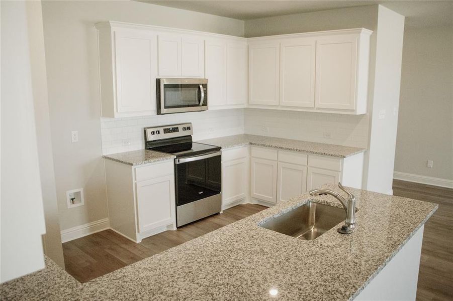 Kitchen with sink, light stone counters, light hardwood / wood-style flooring, white cabinets, and appliances with stainless steel finishes