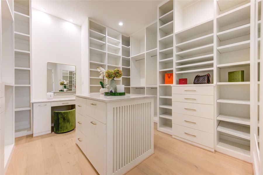 Boutique-inspired dressing room featuring custom floor-to-ceiling cabinetry, a center island, and dedicated vanity space.