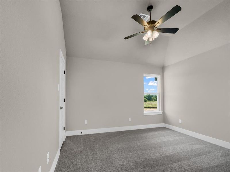 Carpeted spare room with vaulted ceiling and a ceiling fan