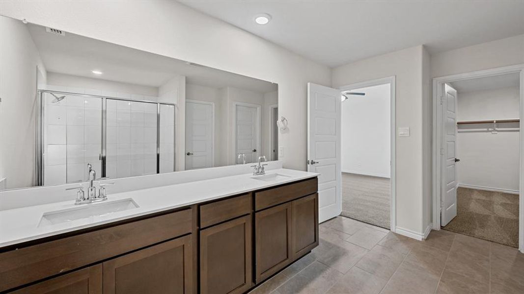 Bathroom featuring a full-width vanity mirror, dual under-mount sinks, a white countertop, and dark wood-finish cabinetry Bathroom featuring a full-width vanity mirror, dual under-mount sinks, a white countertop, and dark wood-finish cabinetry