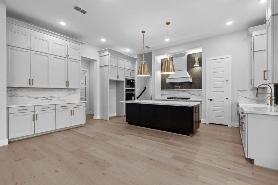 The kitchen features lots of extra storage in the upper cabinets and walk-in pantry. Double ovens make cooking for a crowd easy and convenient, and the porcelain countertops give the space an upscale, sophisticated polish.