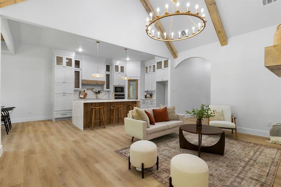 Living room with sink, vaulted ceiling with beams, and light hardwood / wood-style floors