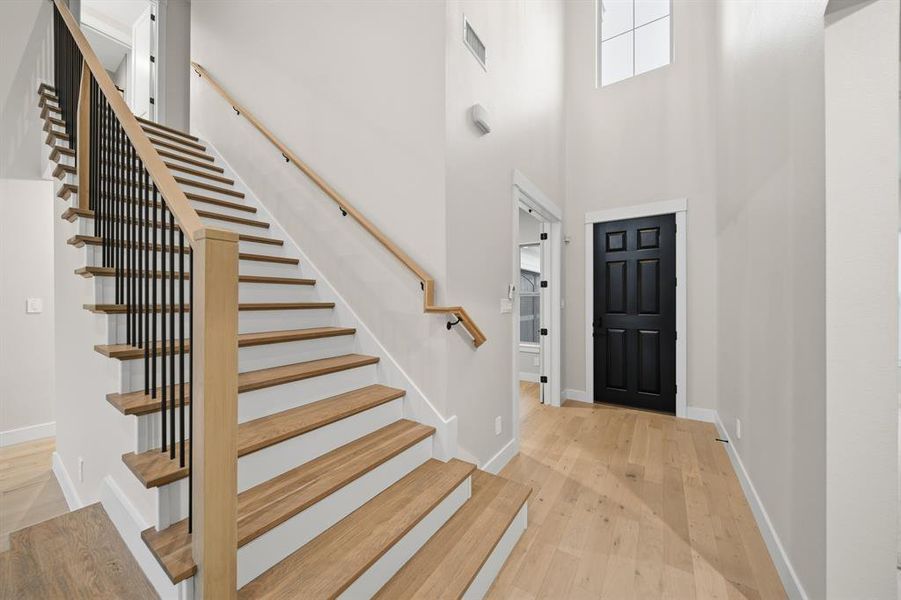 Foyer entrance featuring light wood-style floors, a high ceiling, and stairway