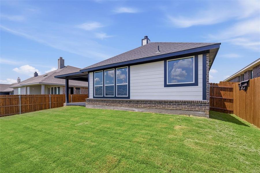 Expansive backyard with a manicured lawn, full wood fencing, a covered patio, and a brick and siding exterior Expansive backyard with a manicured lawn, full wood fencing, a covered patio, and a brick and siding exterior