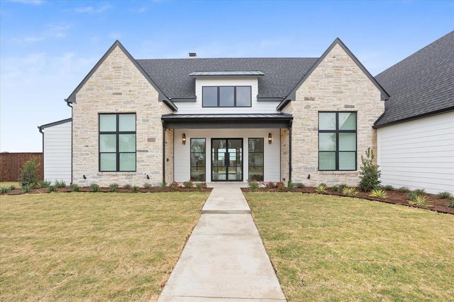 View of front of house featuring stone siding, a standing seam roof, a metal roof, and covered porch