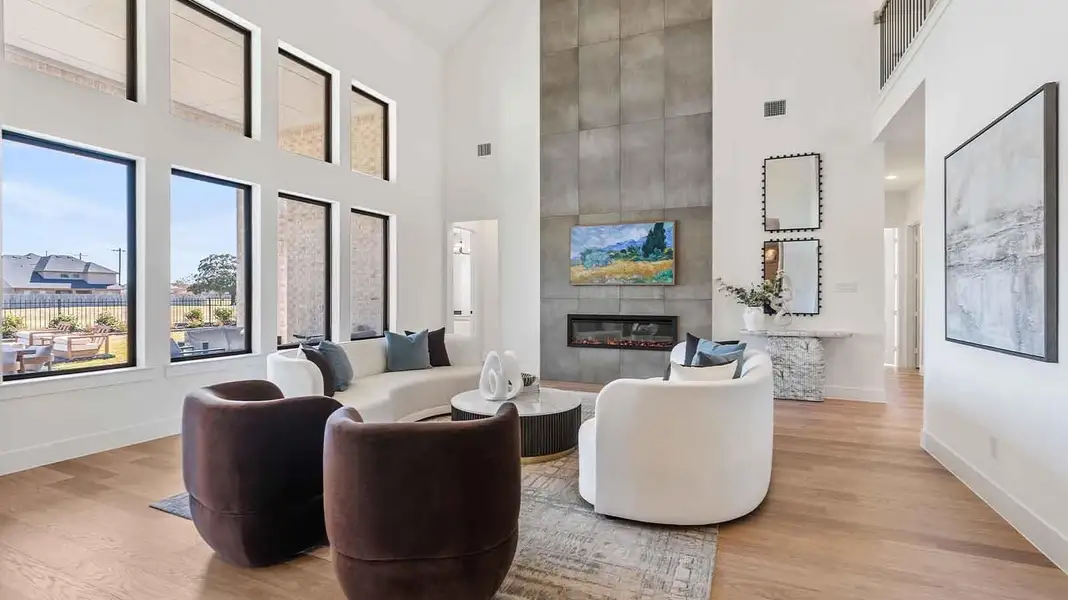Elegant living room with soaring ceilings, a cozy electric fireplace, open-concept design, and seamless flow into a chef-inspired kitchen.