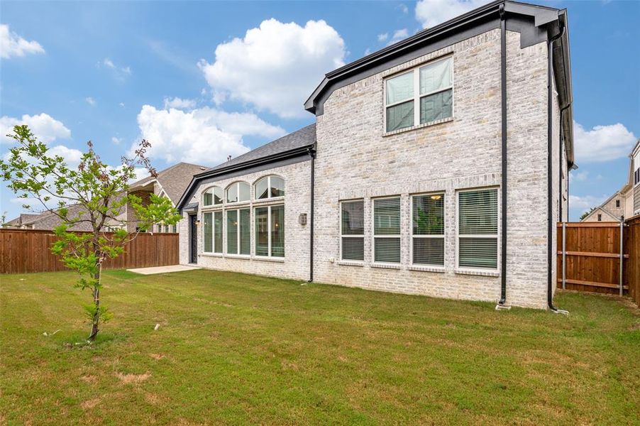 Rear view of property featuring a fenced backyard, brick siding, and a patio