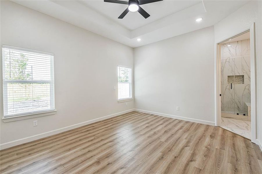 Tray ceiling in Primary Suite with plenty of windows providing natural light.