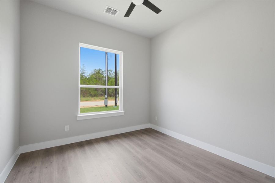 A well-lit room offers clean lines, a contemporary ceiling fan, and durable wood-look flooring. A well-lit room offers clean lines, a contemporary ceiling fan, and durable wood-look flooring.