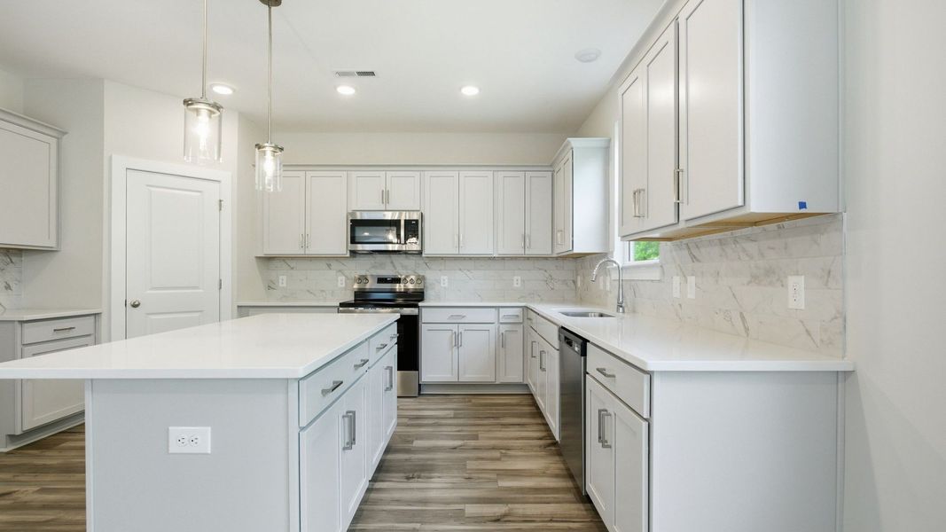 Kitchen with light cabinetry, quartz countertops, tile backsplash, and pantry Kitchen with light cabinetry, quartz countertops, tile backsplash, and pantry
