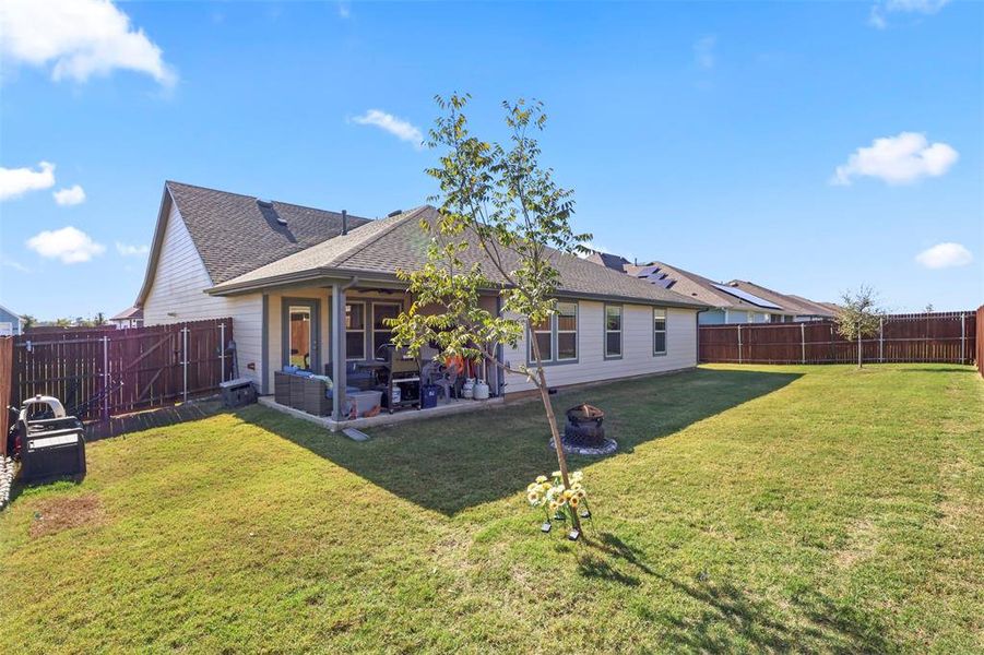 Rear view of house with a patio, a fenced backyard, and a shingled roof
