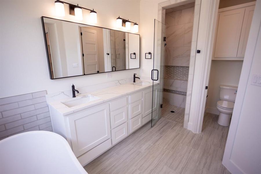 Bathroom featuring a shower stall, a freestanding tub, and double vanity Bathroom featuring a shower stall, a freestanding tub, and double vanity