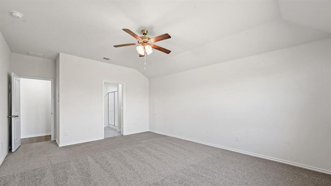 Carpeted room featuring a ceiling fan with light fixture, vaulted ceiling, white walls, and white trim