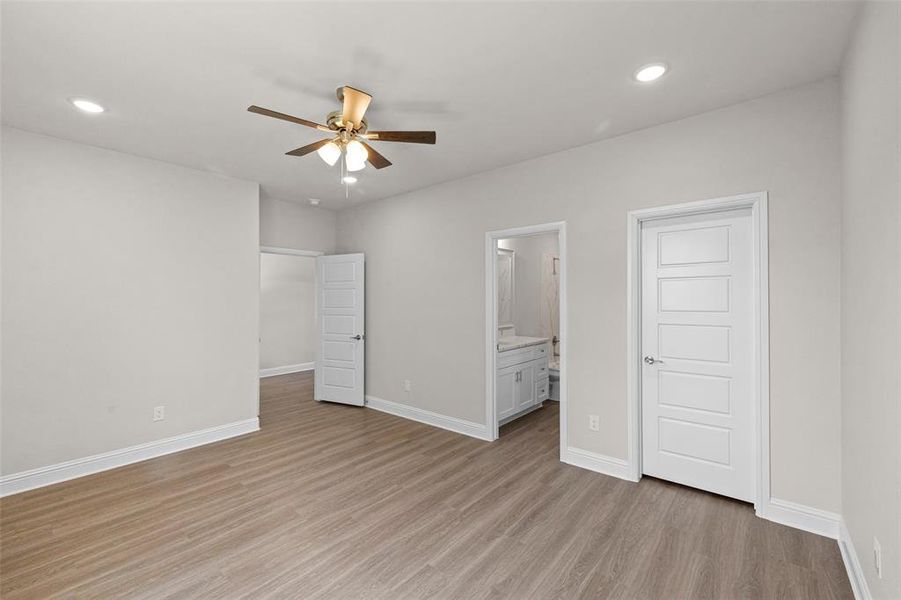 Unfurnished bedroom with ceiling fan, light wood-type flooring, and ensuite bathroom