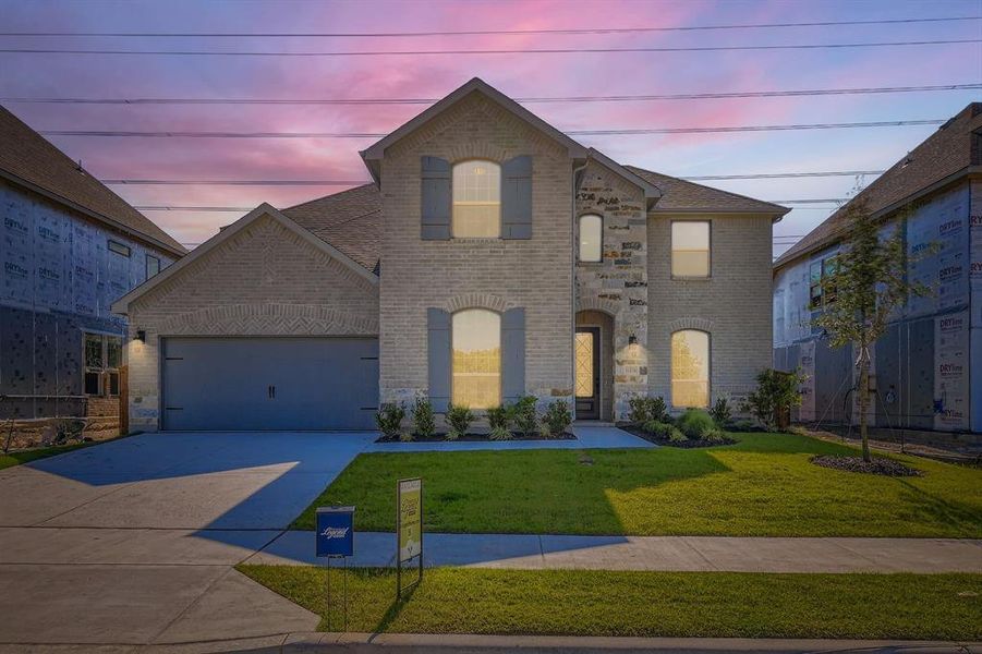 French country style house with brick siding, driveway, an attached garage, and a yard